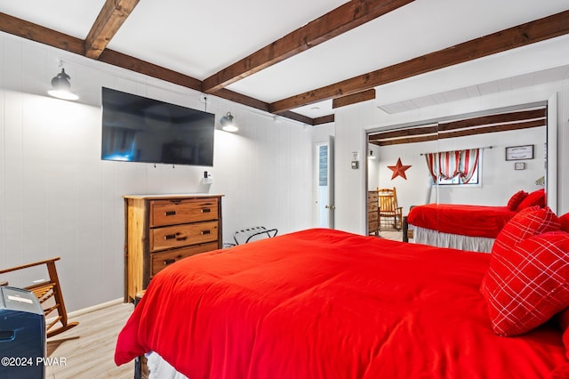 bedroom with beam ceiling and light wood-type flooring