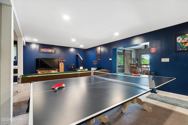 rec room with a barn door, ceiling fan, and light colored carpet