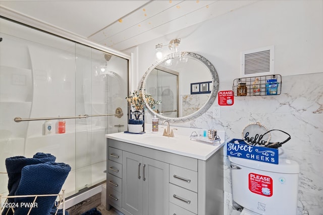 bathroom with vanity, a shower with door, and tile walls