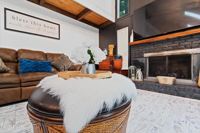 bedroom featuring beam ceiling, wooden ceiling, a high ceiling, light hardwood / wood-style floors, and a fireplace