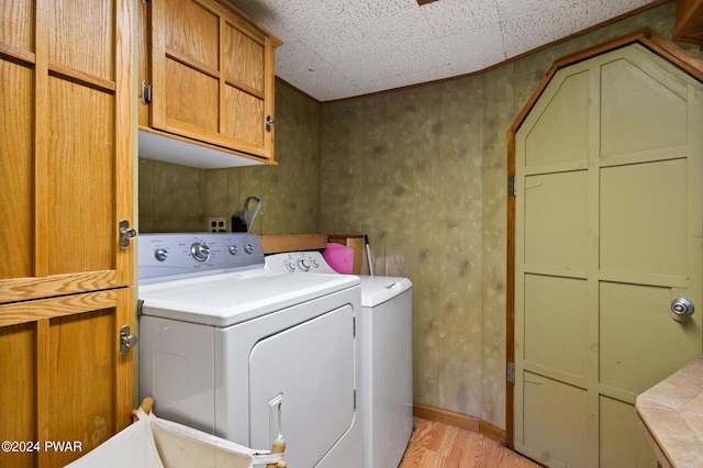 washroom featuring light wood finished floors, separate washer and dryer, cabinet space, and baseboards