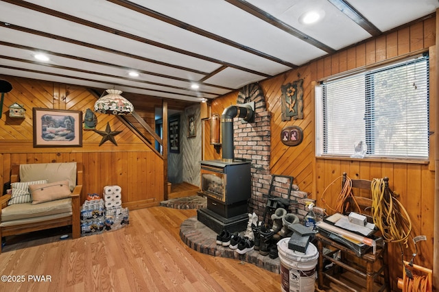 living room featuring a wood stove, light wood-type flooring, wood walls, beam ceiling, and recessed lighting