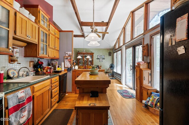 interior space with beam ceiling, light hardwood / wood-style floors, and a wood stove