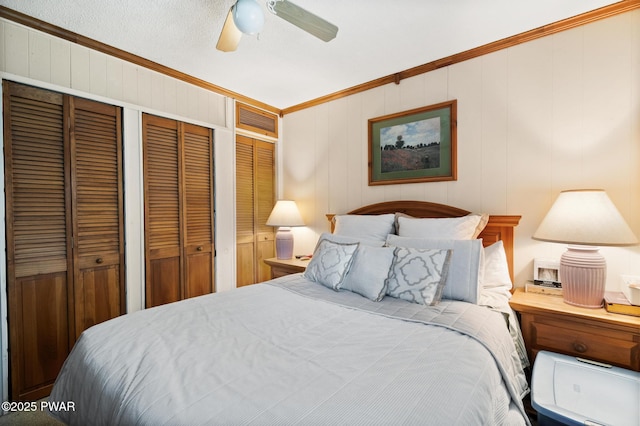 bedroom with multiple closets, ceiling fan, wooden walls, and ornamental molding