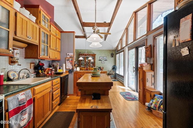 kitchen with hanging light fixtures, black appliances, a sink, and glass insert cabinets