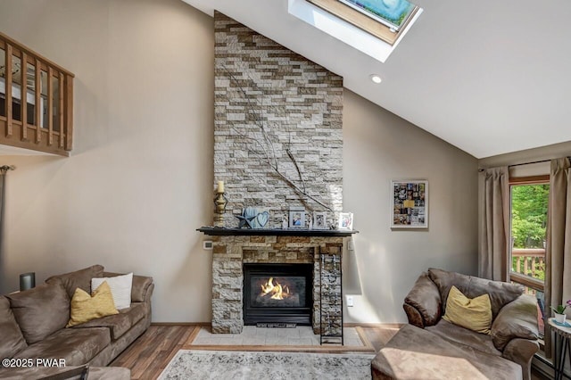 living room with a skylight, high vaulted ceiling, light wood-type flooring, a baseboard radiator, and a fireplace