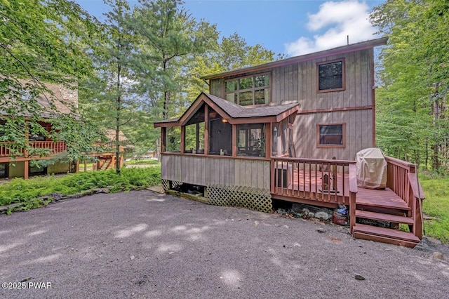 rear view of property featuring a wooden deck and a sunroom