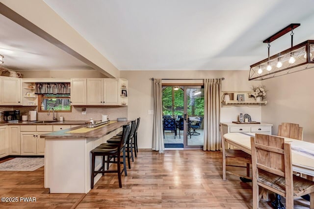 kitchen with pendant lighting, decorative backsplash, wood-type flooring, and a kitchen breakfast bar