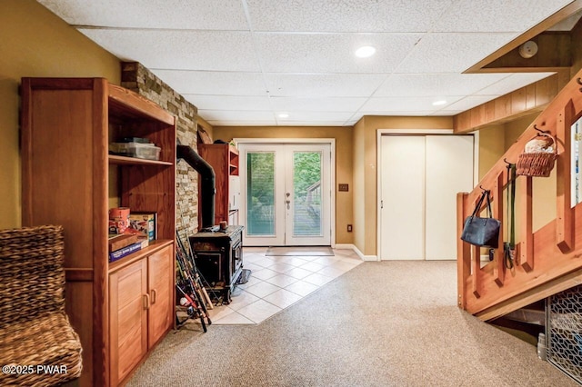 interior space featuring a paneled ceiling, french doors, and a wood stove