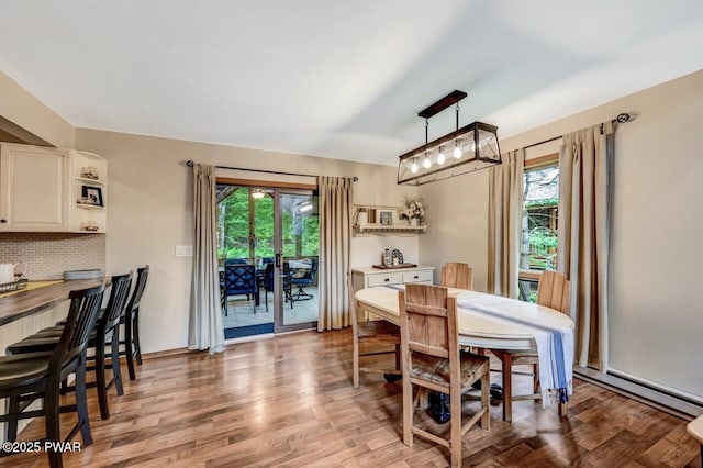 dining space featuring a baseboard radiator, plenty of natural light, and light hardwood / wood-style flooring