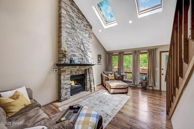 living room featuring high vaulted ceiling, hardwood / wood-style floors, a fireplace, and a skylight