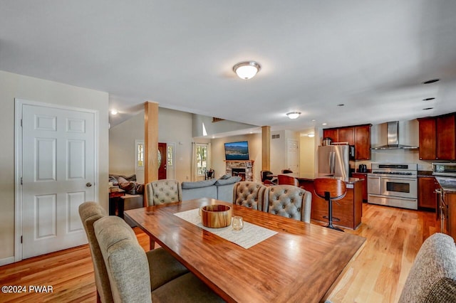 dining room featuring a stone fireplace and light hardwood / wood-style flooring