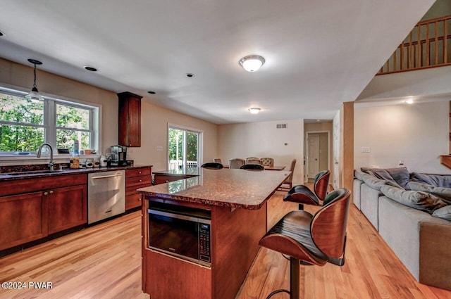 kitchen with built in microwave, sink, dishwasher, a center island, and light hardwood / wood-style floors