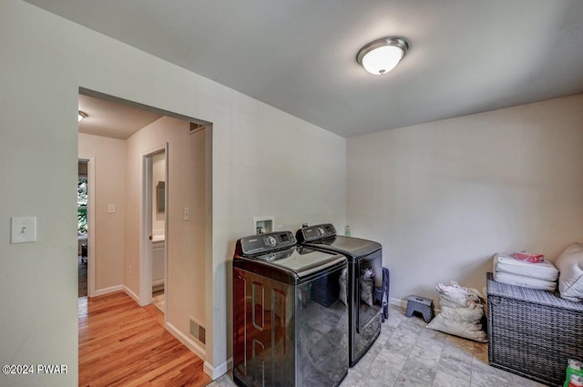 laundry area featuring washing machine and dryer and light wood-type flooring