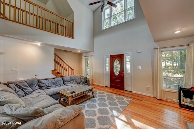 living room with ceiling fan, wood-type flooring, and a towering ceiling