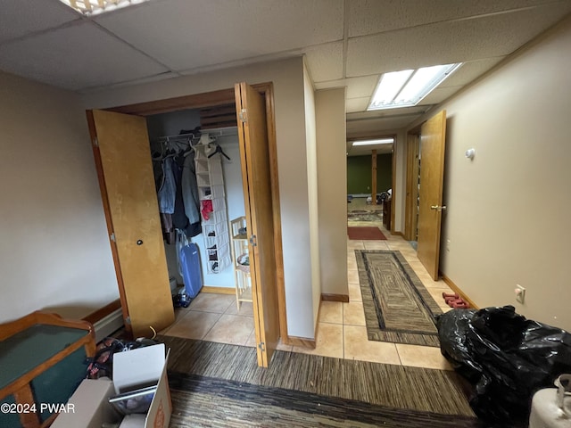 hall featuring a paneled ceiling and light tile patterned floors