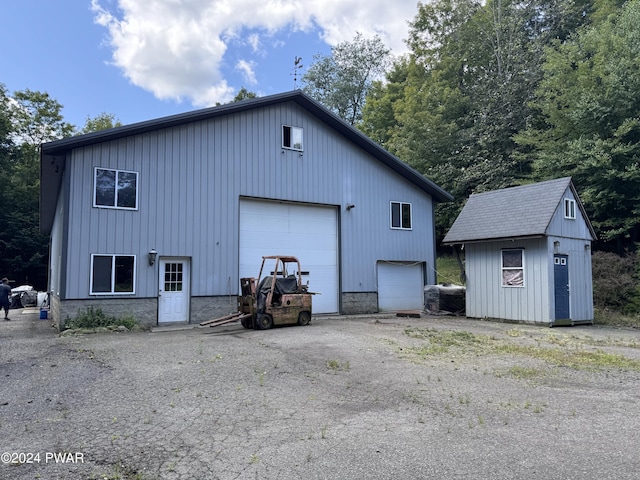 rear view of house featuring a garage and an outbuilding