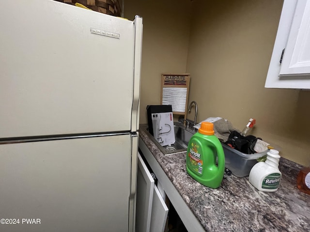 kitchen featuring white cabinets, white refrigerator, and dark stone counters