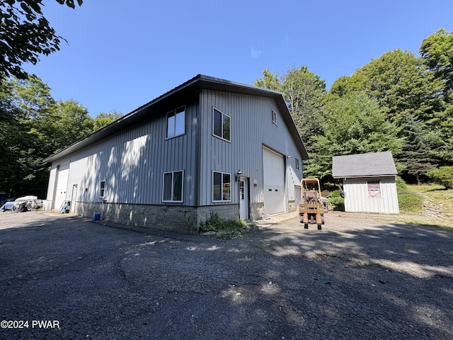 view of property exterior featuring a garage, a shed, and an outbuilding