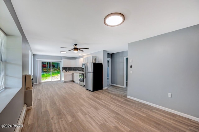 kitchen featuring light wood-type flooring, backsplash, stainless steel appliances, a baseboard heating unit, and white cabinets