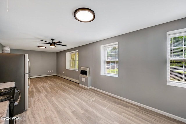 unfurnished living room featuring light hardwood / wood-style floors, heating unit, and ceiling fan