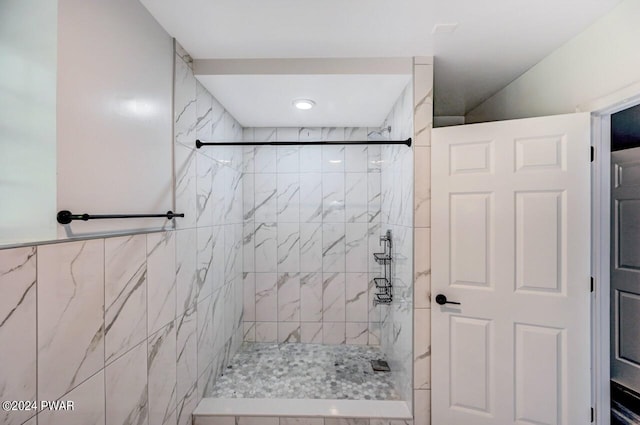 bathroom with a tile shower and tile walls