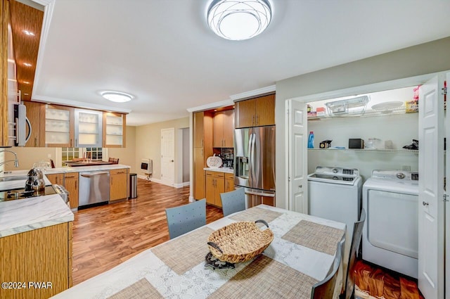 kitchen with heating unit, washer and dryer, stainless steel appliances, and light hardwood / wood-style flooring