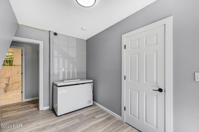 clothes washing area with light hardwood / wood-style flooring