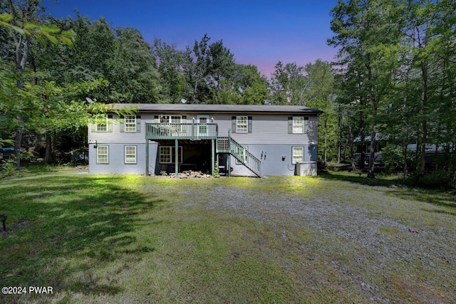 back house at dusk with a yard and a wooden deck