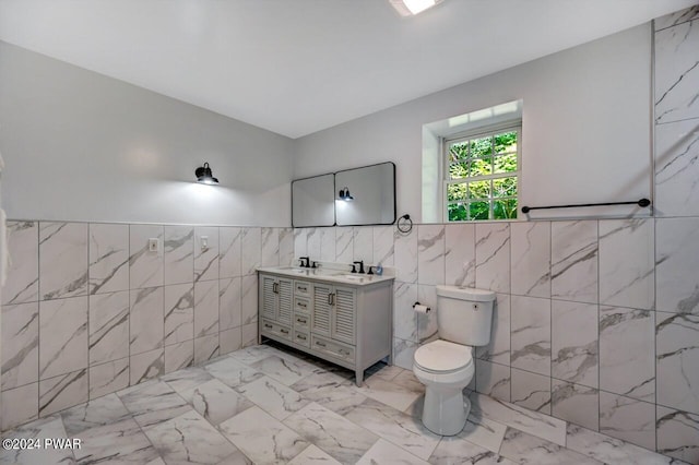 bathroom with vanity, toilet, and tile walls