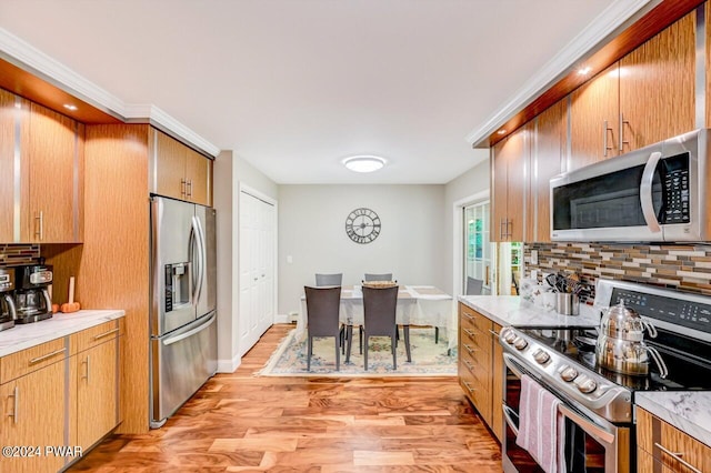 kitchen with crown molding, decorative backsplash, light hardwood / wood-style flooring, and stainless steel appliances