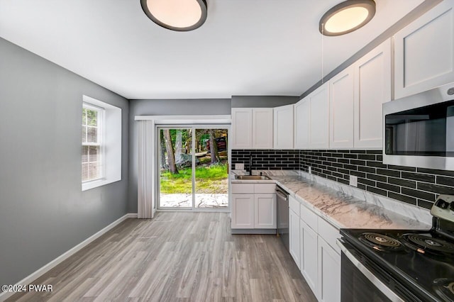 kitchen featuring sink, stainless steel appliances, light hardwood / wood-style flooring, backsplash, and white cabinets