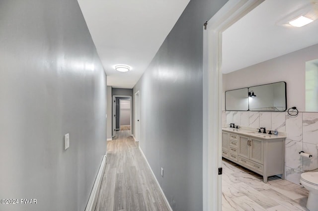 hall with tile walls and sink