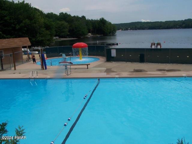 pool with a water view, fence, and a patio