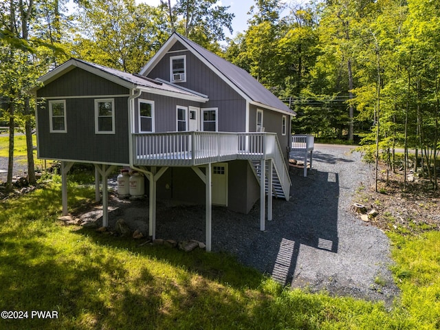 back of property featuring a deck, metal roof, a lawn, and stairs