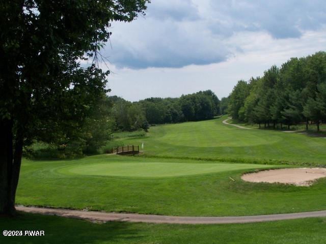 view of home's community featuring golf course view and a lawn