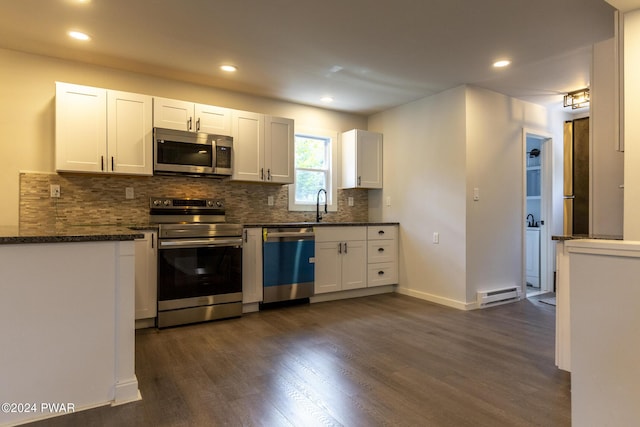 kitchen with tasteful backsplash, white cabinets, a baseboard radiator, appliances with stainless steel finishes, and dark wood-style flooring