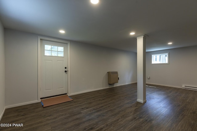 basement with dark hardwood / wood-style floors, heating unit, and baseboard heating