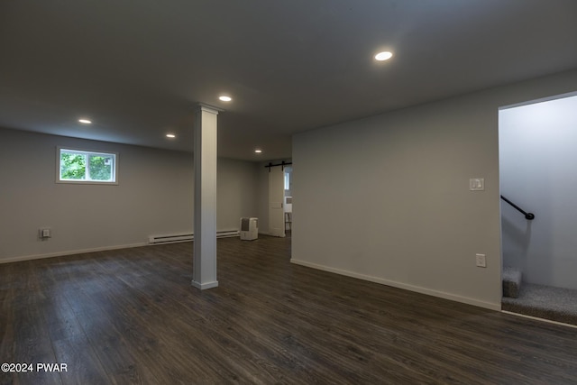 basement with dark hardwood / wood-style floors, a barn door, and a baseboard heating unit