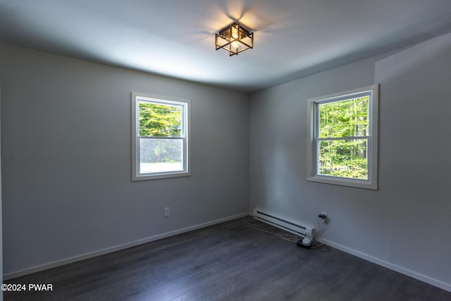 spare room with dark wood finished floors, baseboards, baseboard heating, and a wealth of natural light