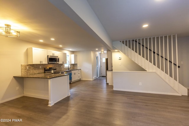 kitchen with tasteful backsplash, dark wood finished floors, a peninsula, stainless steel appliances, and white cabinetry