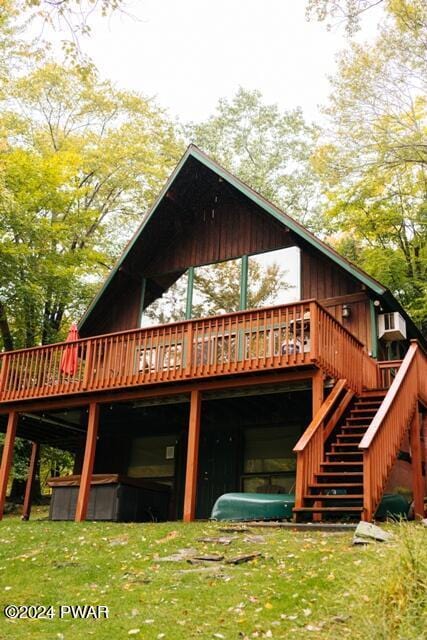 back of property with a hot tub and a deck