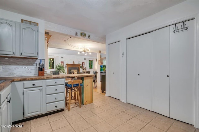 102 Keystone Ct, Dingmans Ferry, PA 18328 - kitchen with a peninsula, a chandelier, light tile patterned floors, decorative backsplash, and open floor plan