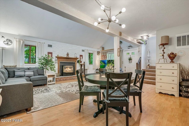 102 Keystone Ct, Dingmans Ferry, PA 18328 - dining room with a textured ceiling, lofted ceiling, light wood-type flooring, a chandelier, and a fireplace