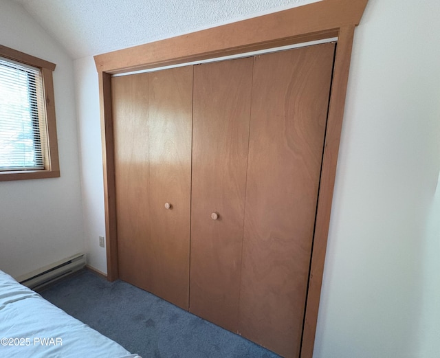 unfurnished bedroom with a baseboard heating unit, a closet, carpet floors, lofted ceiling, and a textured ceiling