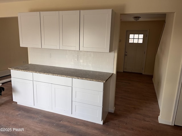 kitchen featuring white cabinets, decorative backsplash, dark hardwood / wood-style flooring, and dark stone countertops