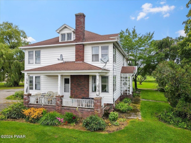 rear view of house featuring a yard and covered porch