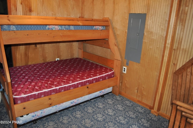 carpeted bedroom featuring electric panel and wooden walls