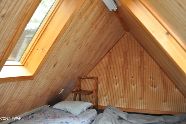 bedroom featuring lofted ceiling and wood walls