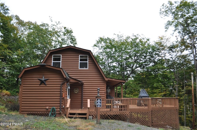 rear view of property with a wooden deck and a gambrel roof